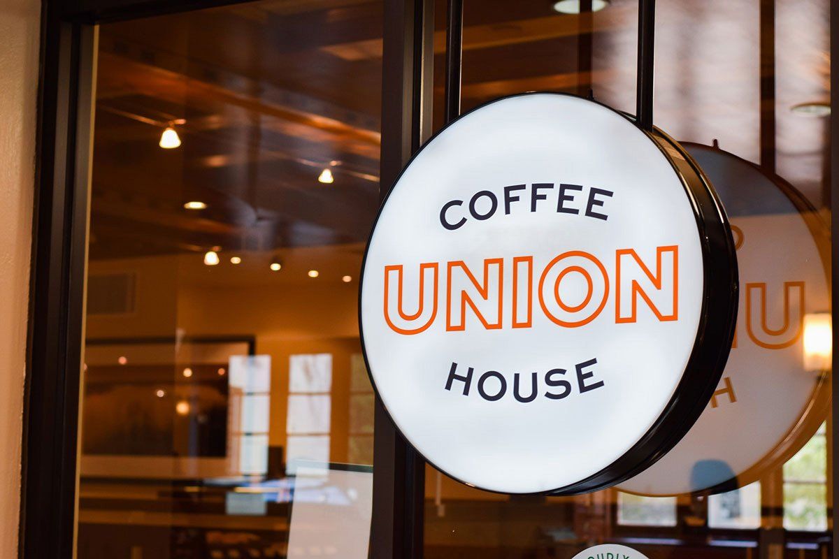 Round hanging sign reading “Coffee Union House” outside café window