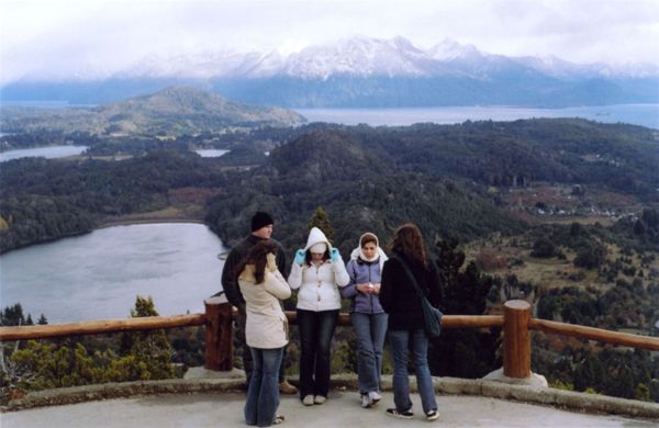 Group of people standing at a scenic overlook above lakes and mountains