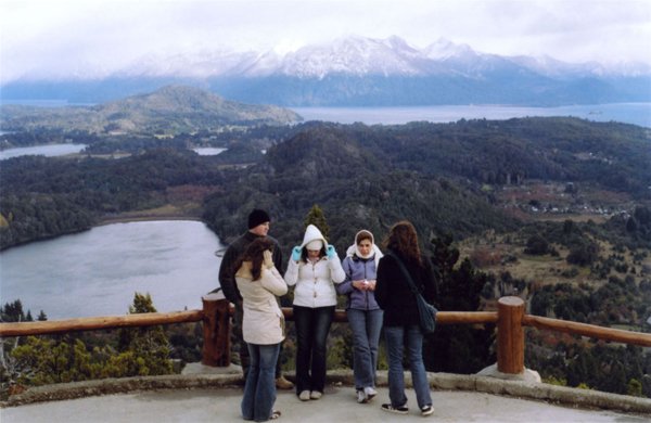 Group of people standing at a scenic overlook above lakes and mountains