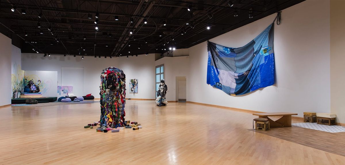 Installation view of sculptures and expansive, slumped blue patchwork