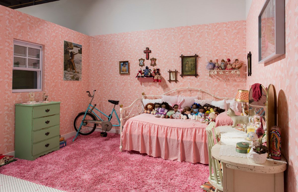 Installation view of pink bedroom with more than a dozen black dolls