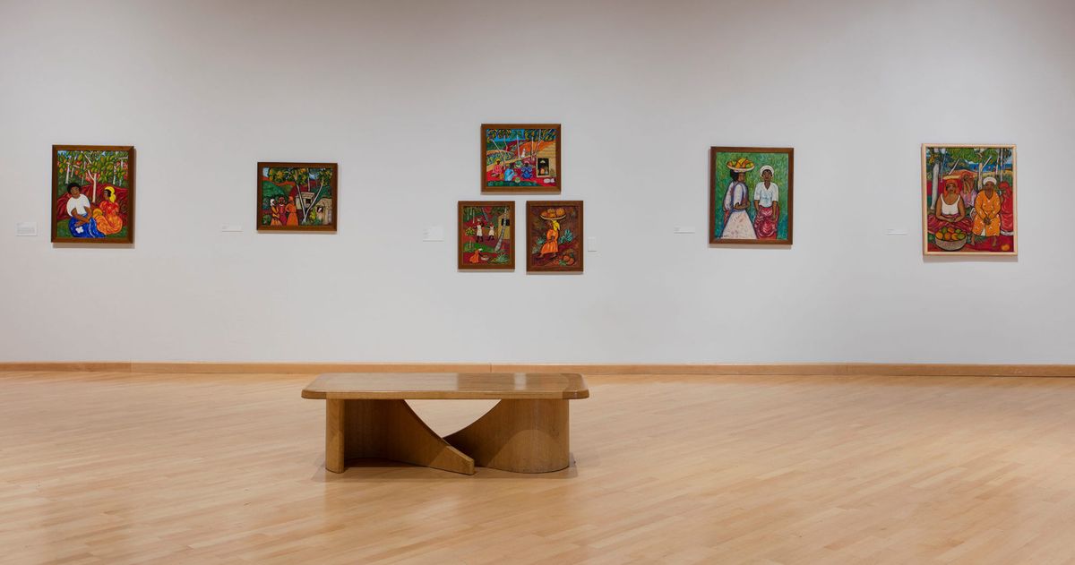 Exhibition view of framed paintings and seating