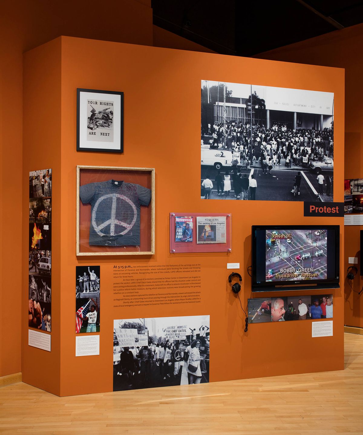 Exhibition view of photos, monitor, audio element, and wall text