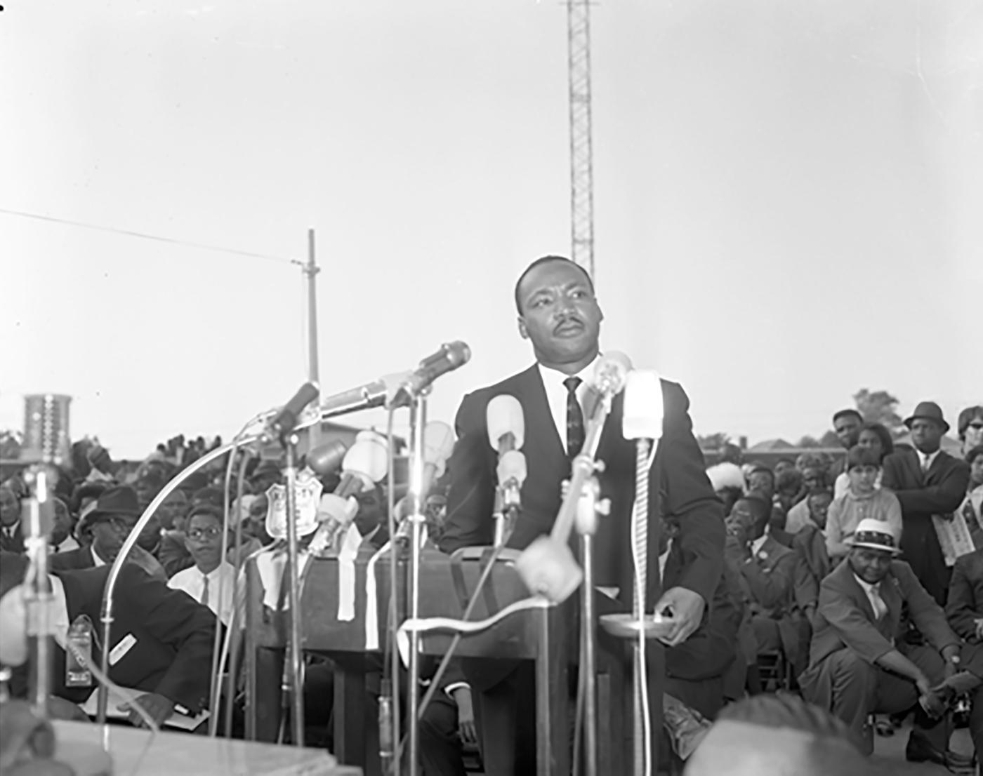 Dr. Martin Luther King Jr. behind a dozen microphones addressing large crowd