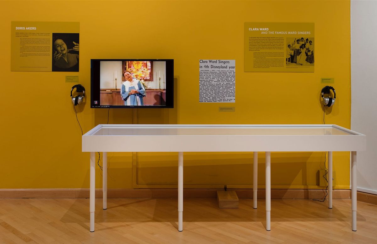 Installation view of monitor, photo elements, audio elements, and vitrines