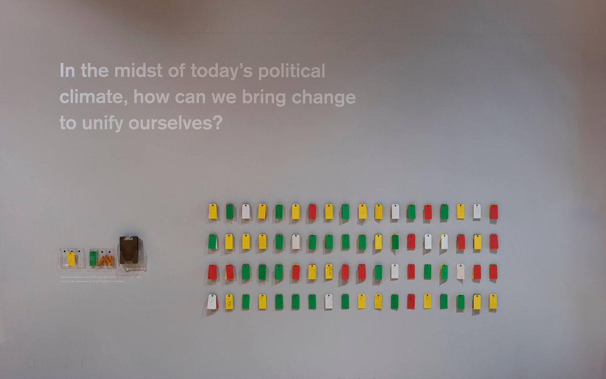 Sharing wall with red, yellow, green, and white tags for sharing response to the exhibition
