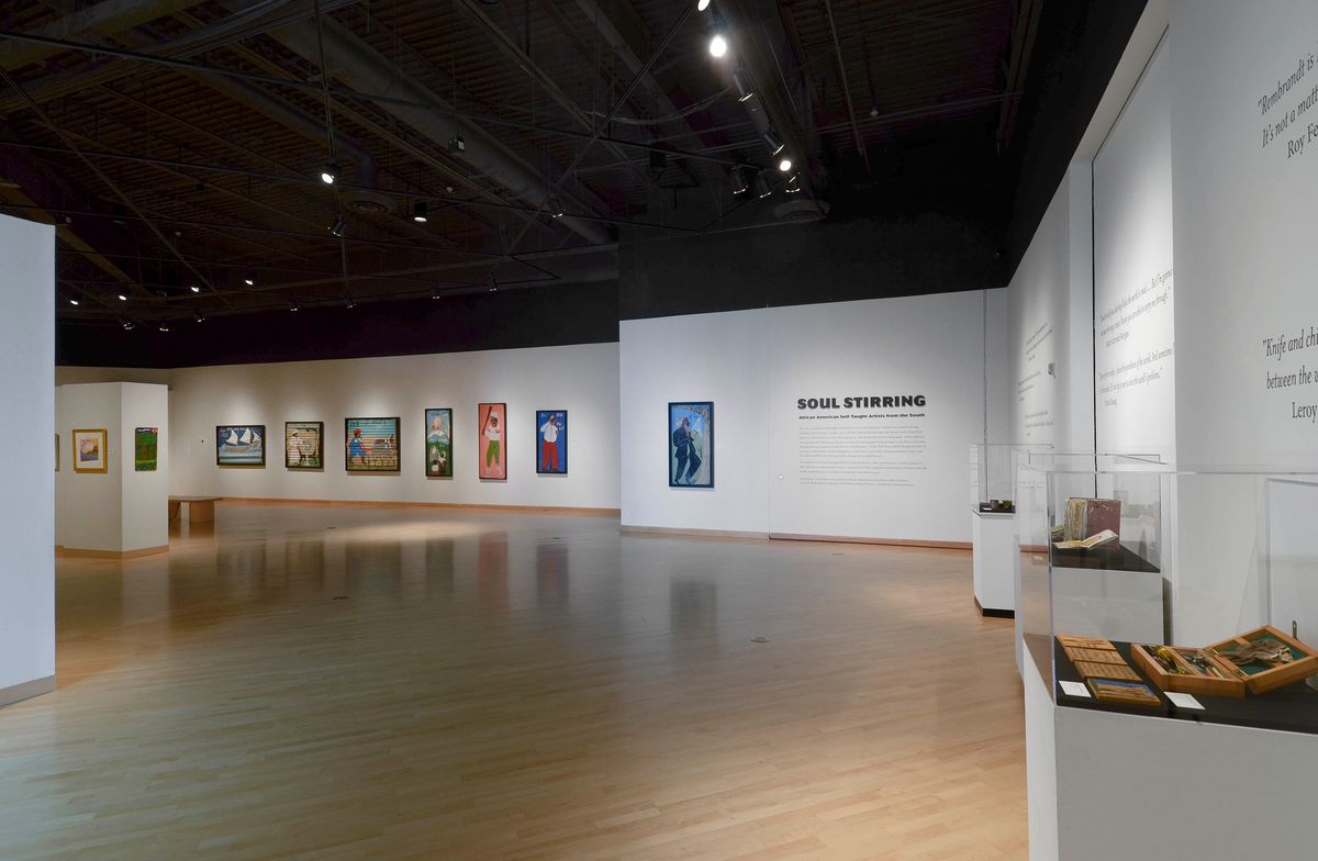 Installation view of paintings, wall text, and vitrines