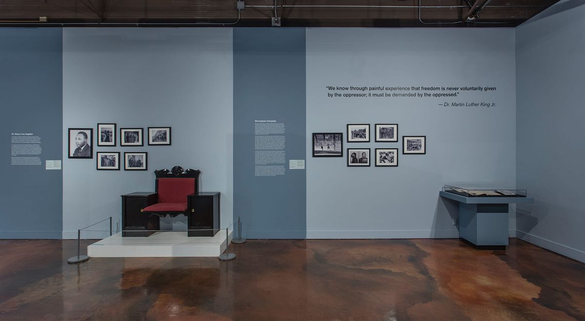 Installation view of wall text, photos, and red chair