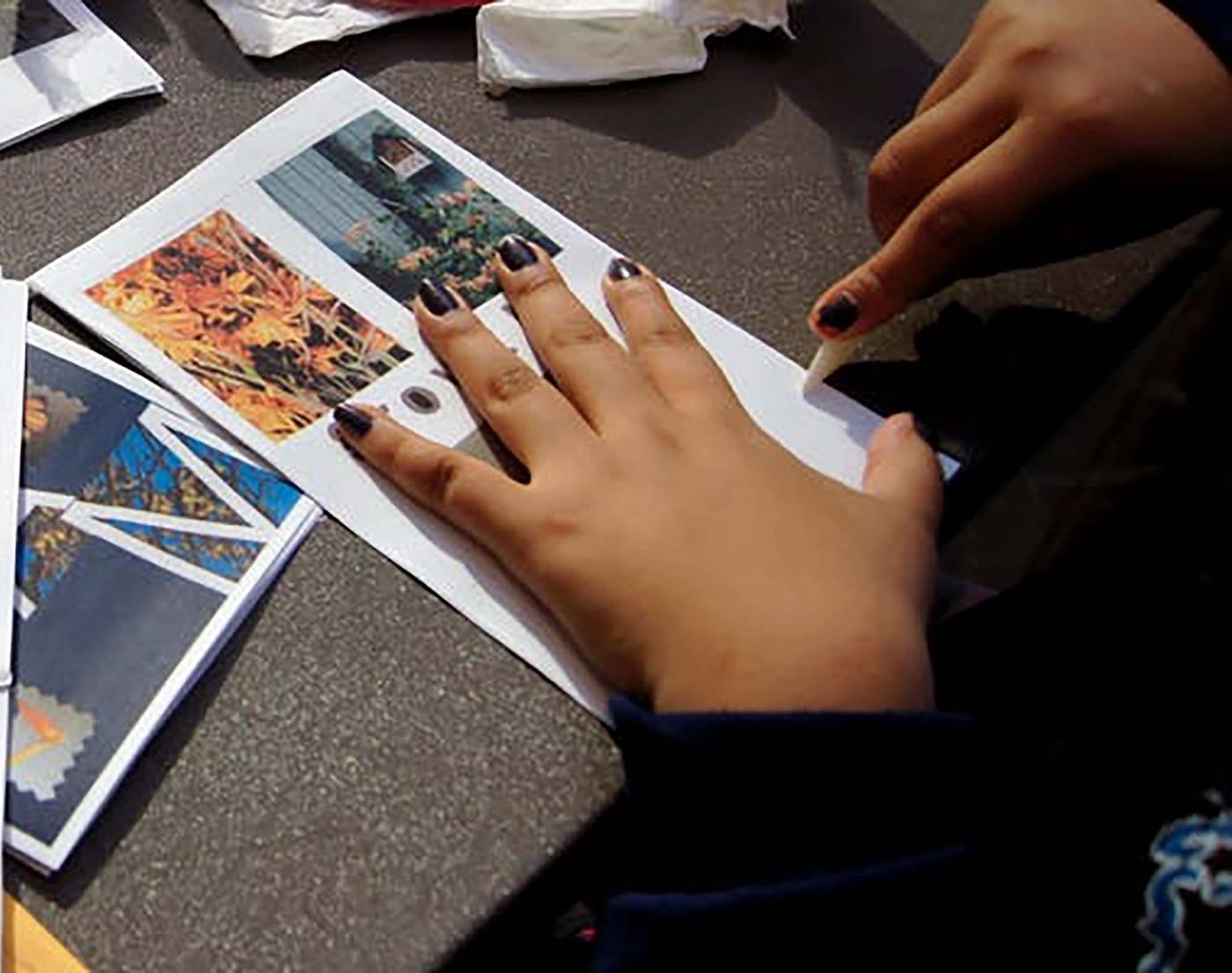 Image of hands cutting paper and images to craft a zine