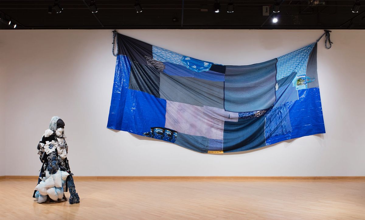 Installation view of human figure made of stuffed bags and blue patchwork
