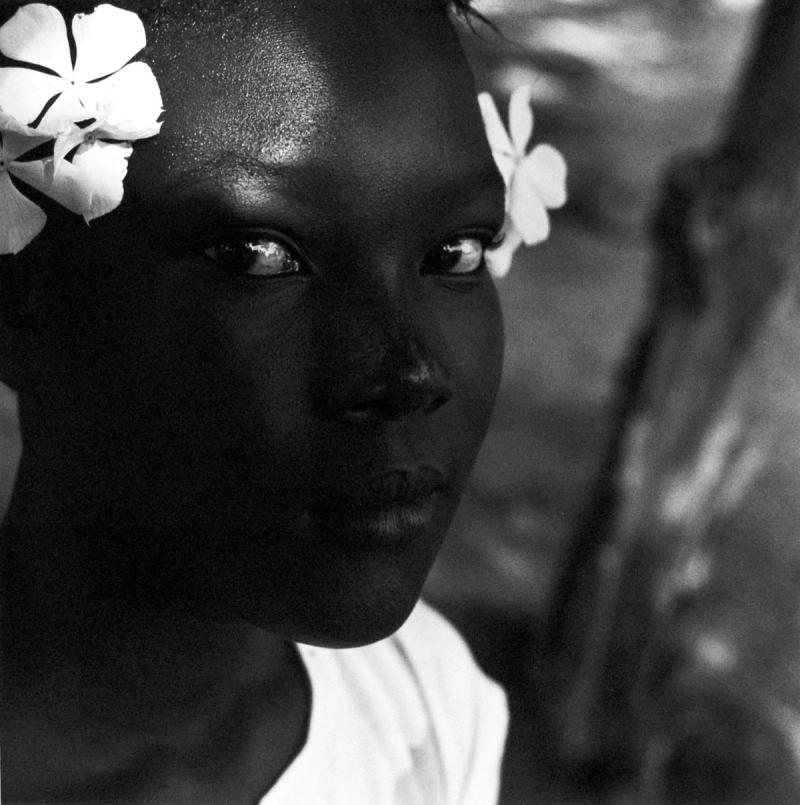Close up of black girl dressed in white with white flowers in her hair