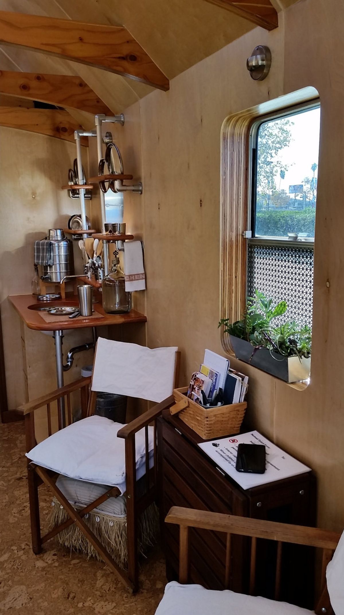 Installation view of interior showing seating area, window, and  collection of reading materials