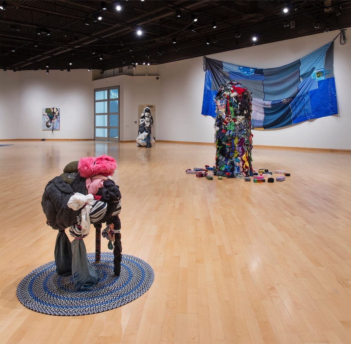 Installation view of three sculptures and expansive, slumped blue patchwork