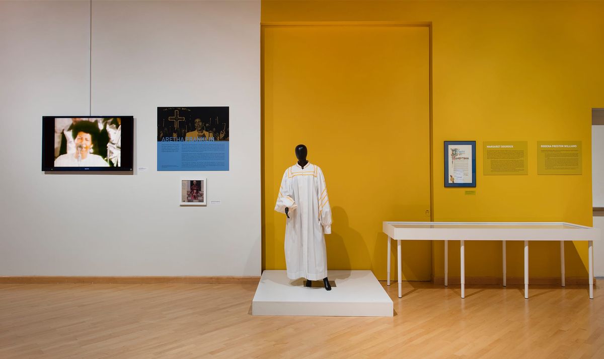 Installation view or choir robe, vitrine, monitor, and photo elements