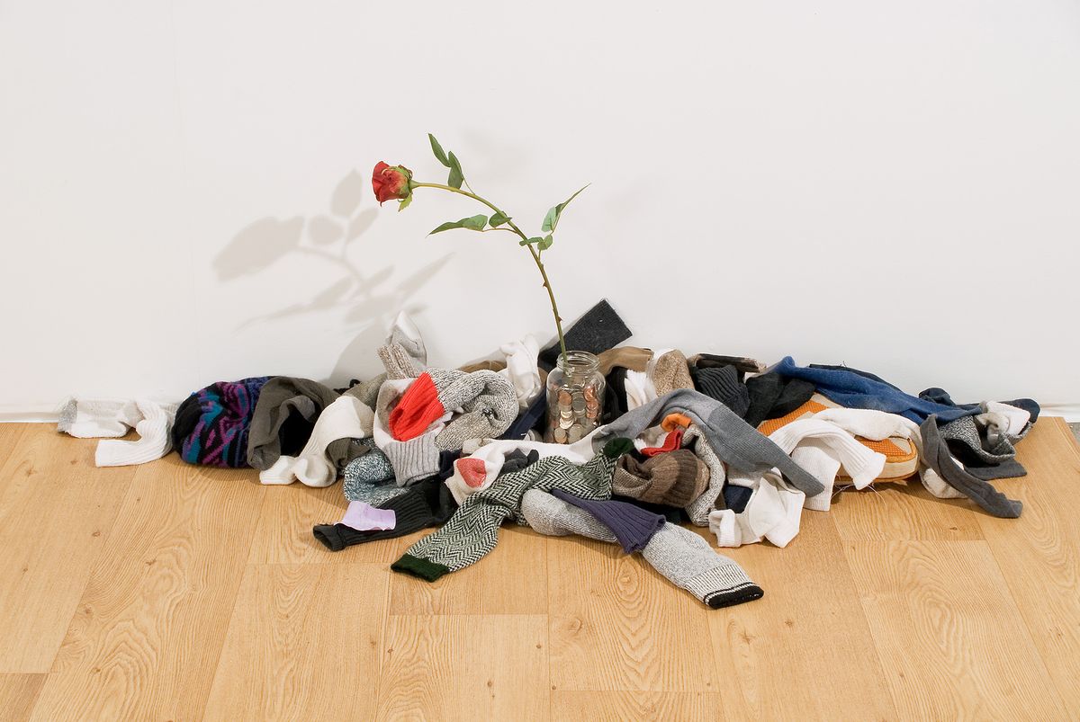 Installation view of jumbled clothing with a rose in the middle