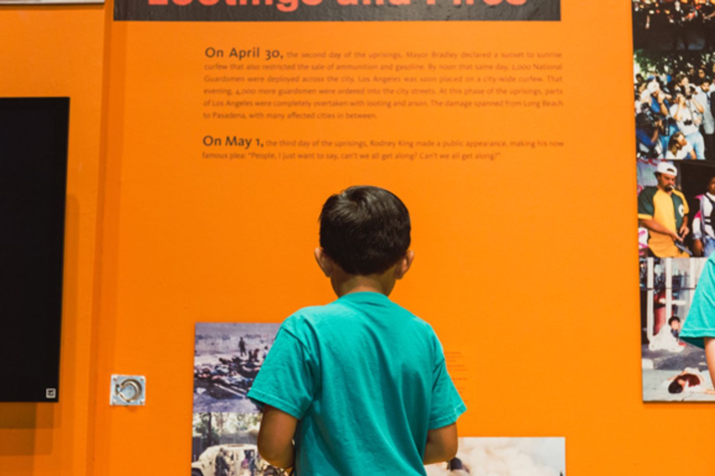 Child in green shirt reading wall text on orange wall