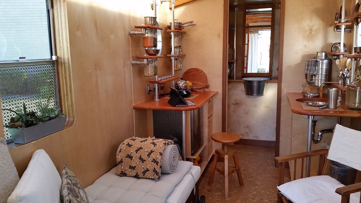 Interior view of installation showing daybed, kitchenette, and window
