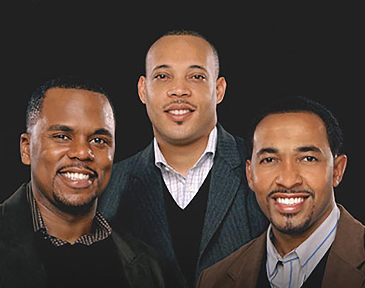 Three well-dressed young black men smiling at viewer