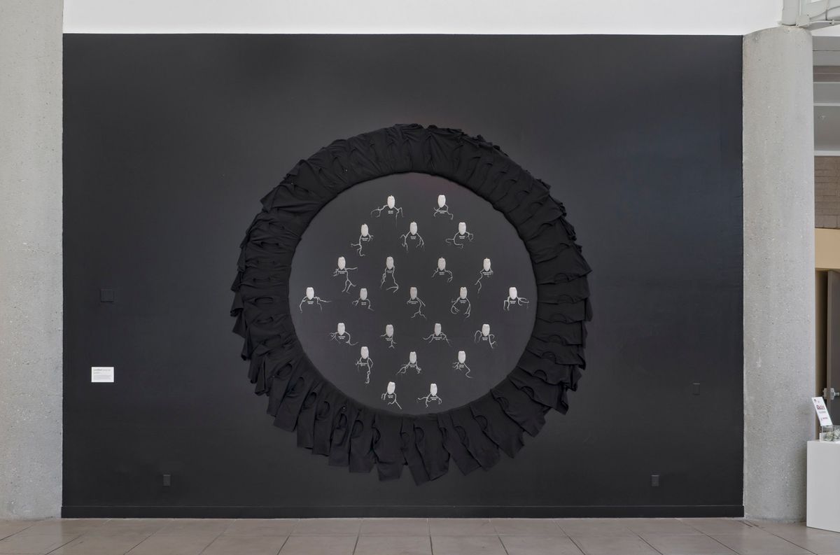 Mural sized installation of black wall with black painted circle with contrasting grey content in the circle