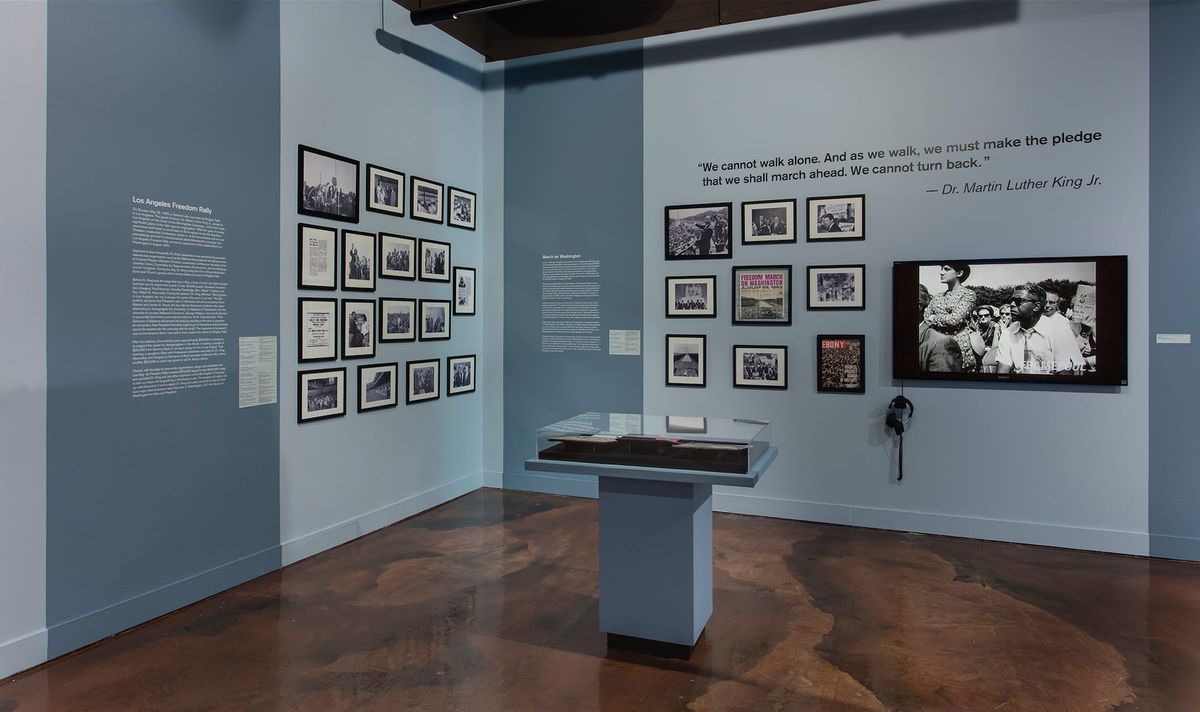 Installation view of monitor, photo elements, audio elements, and vitrines