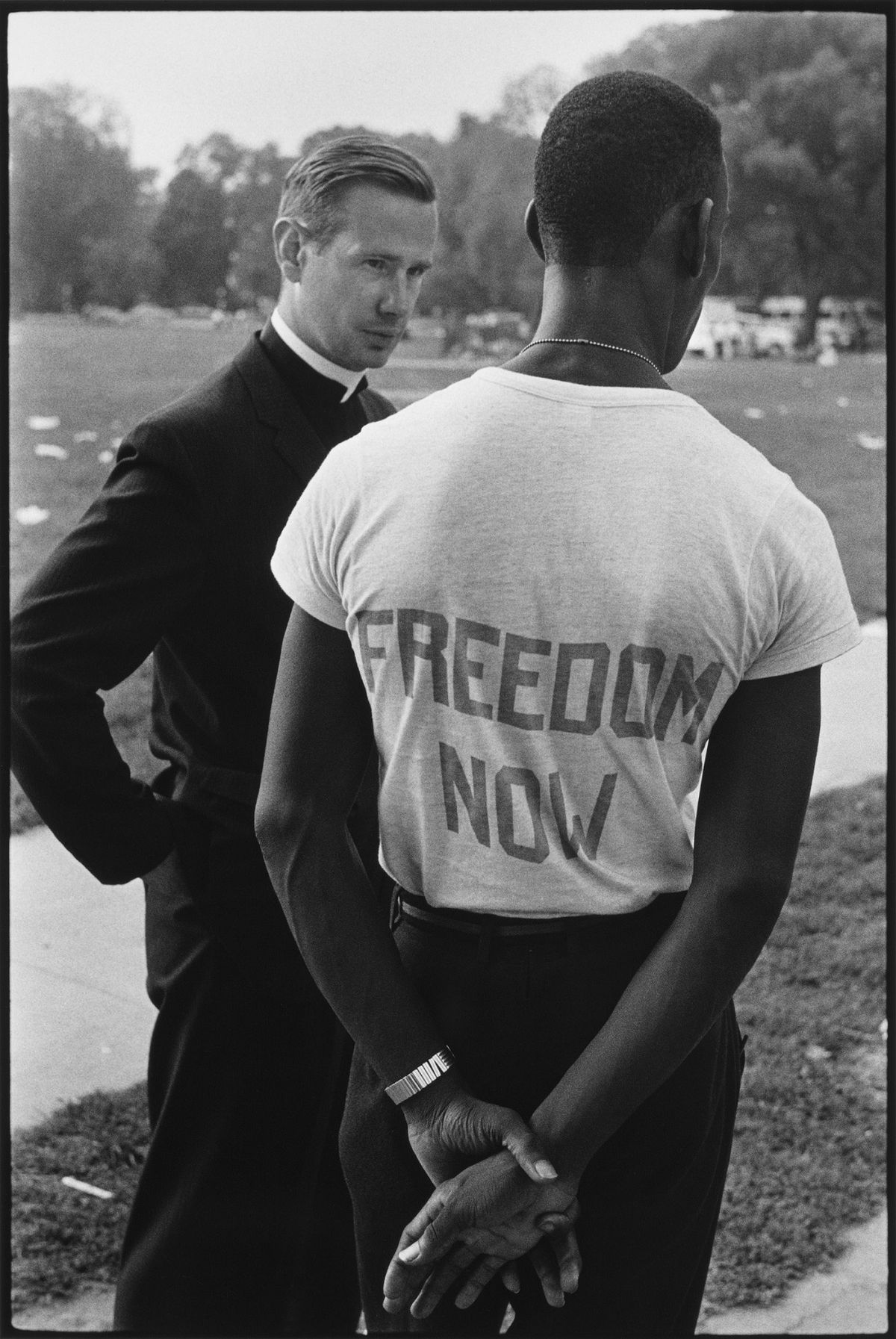 Young black man and a white priest in conversation in a park