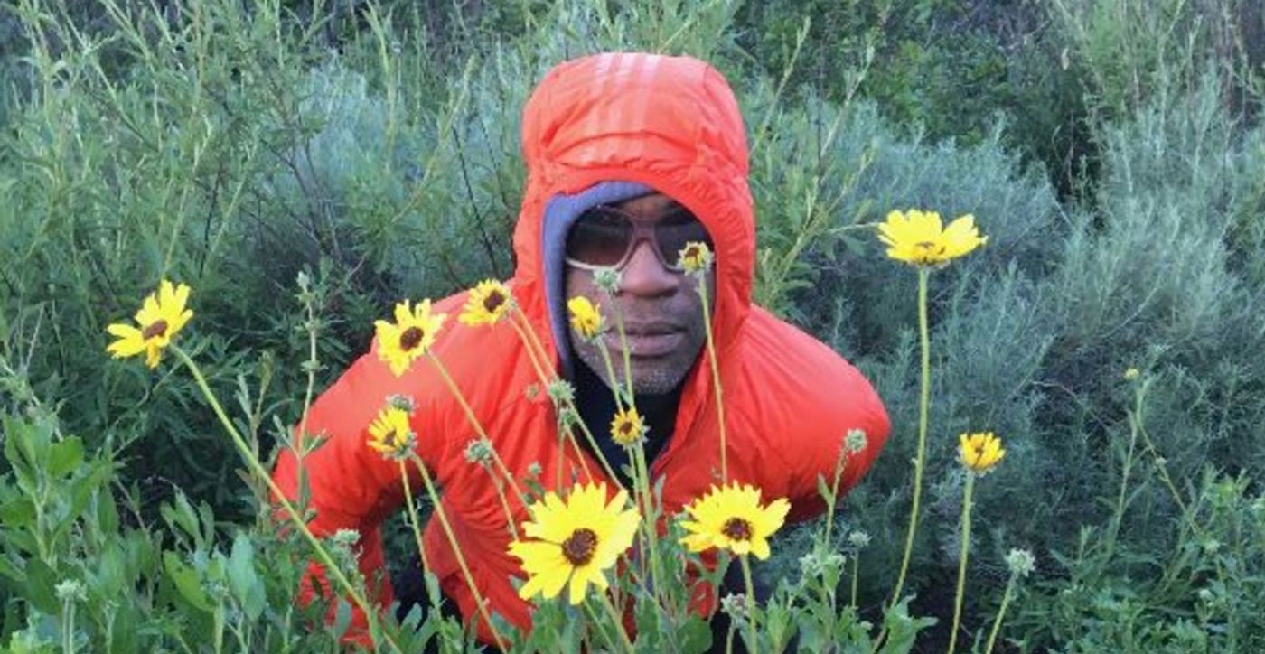 Karl Jean-Guerly Pétion wearing red hoodie and sunnies in field of wildflowers