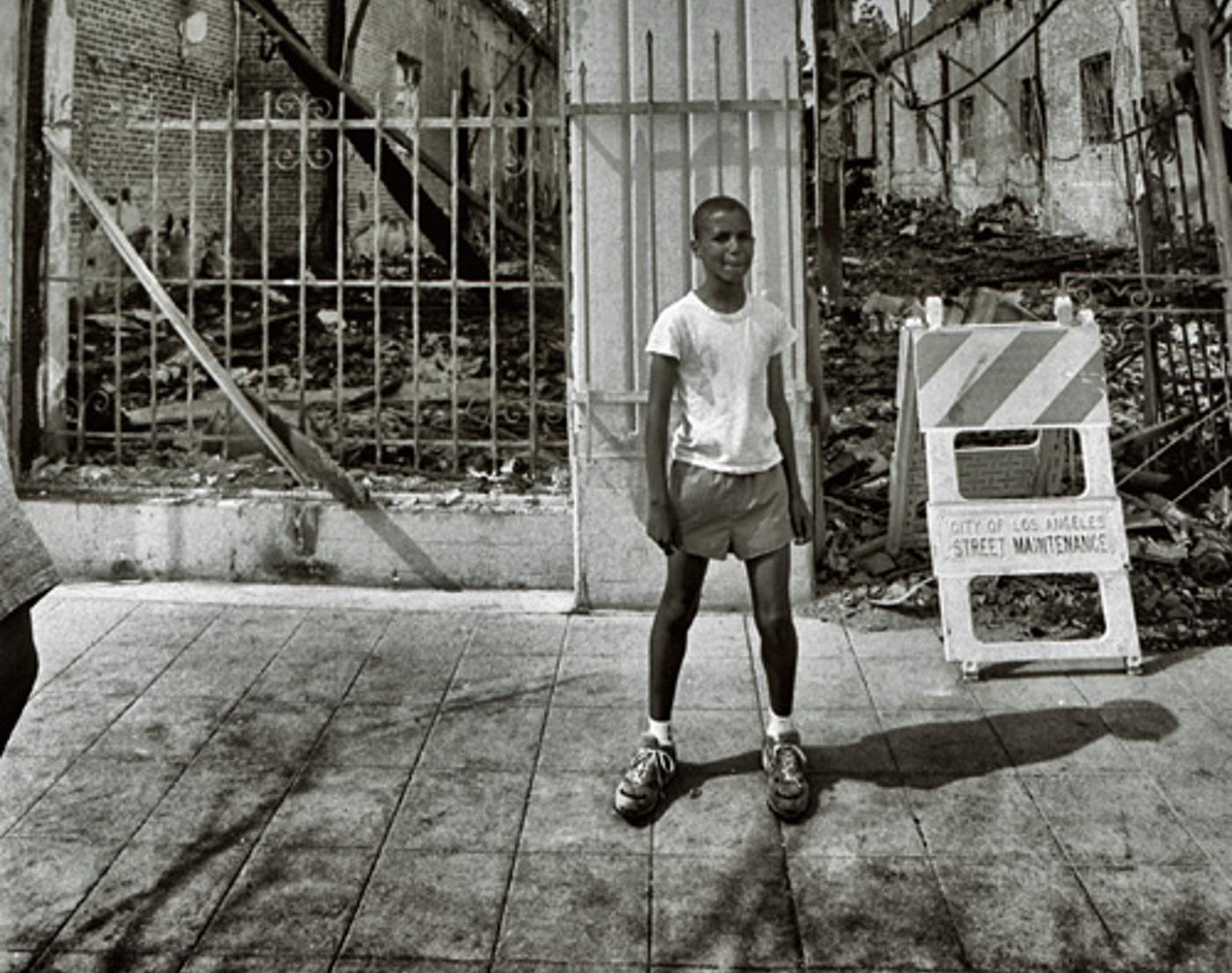 Boy dressed for summer in front of newly burned building rubble (ca. 1992)