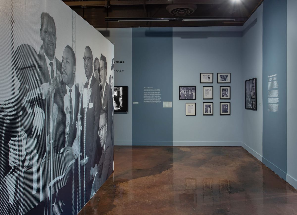 Large scale blow up of Dr. Martin Luther King Jr. at microphones with his political counterparts