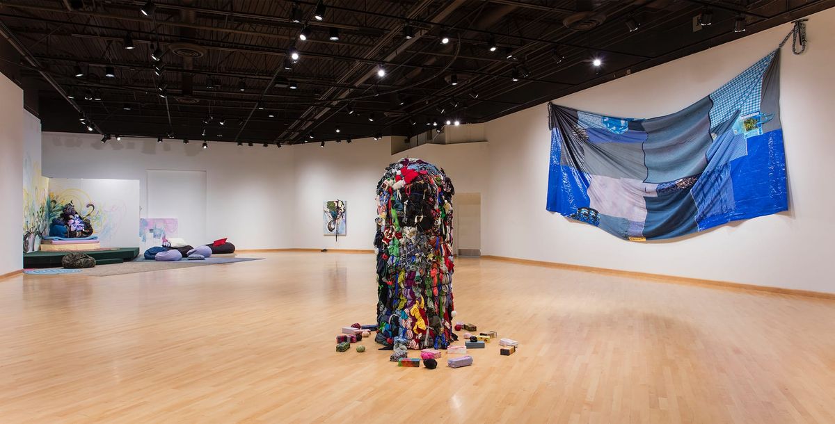 Installation view of  sculptures and expansive, slumped blue patchwork