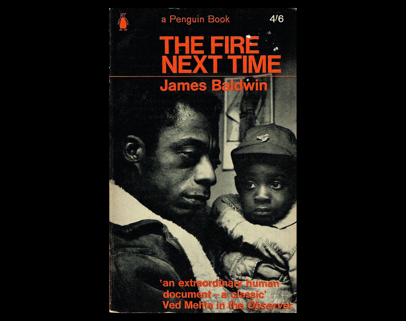 James Baldwin in profile holding a baby boy wearing a ball cap