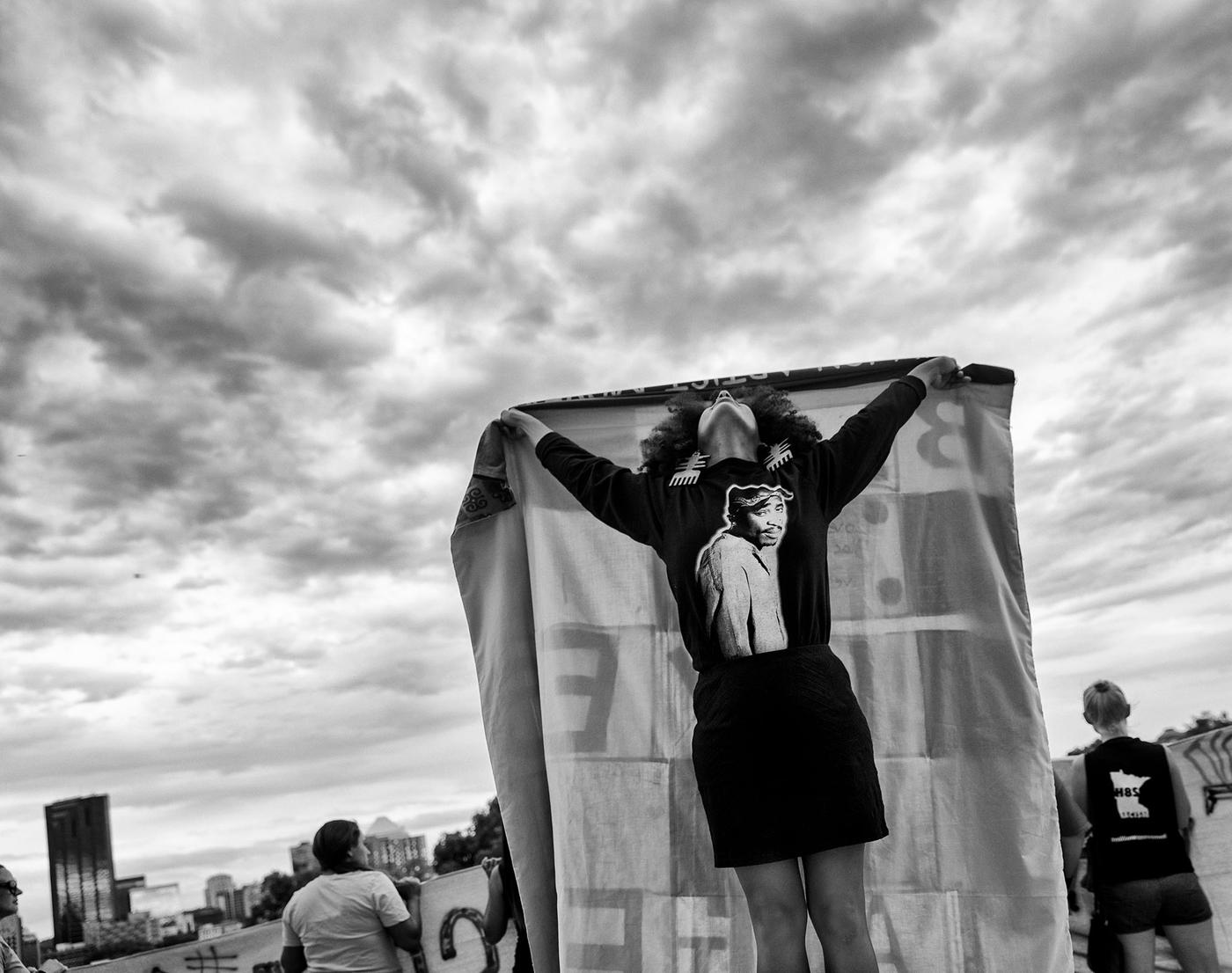 Woman looking to the skies holding cloth banner at rally