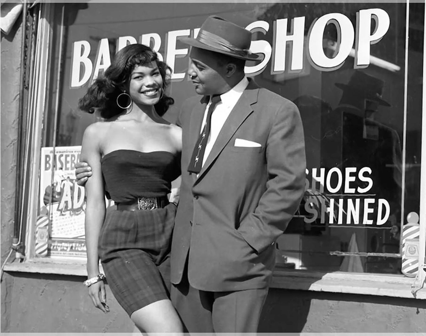 Couple smiling in front of a barber shop window