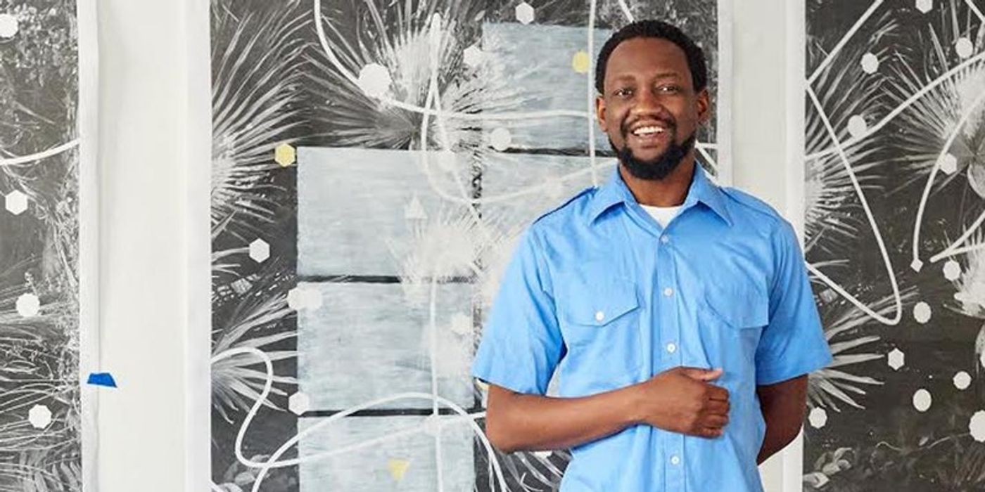 Adler Guerrier wearing blue shirt in front of patterned wall