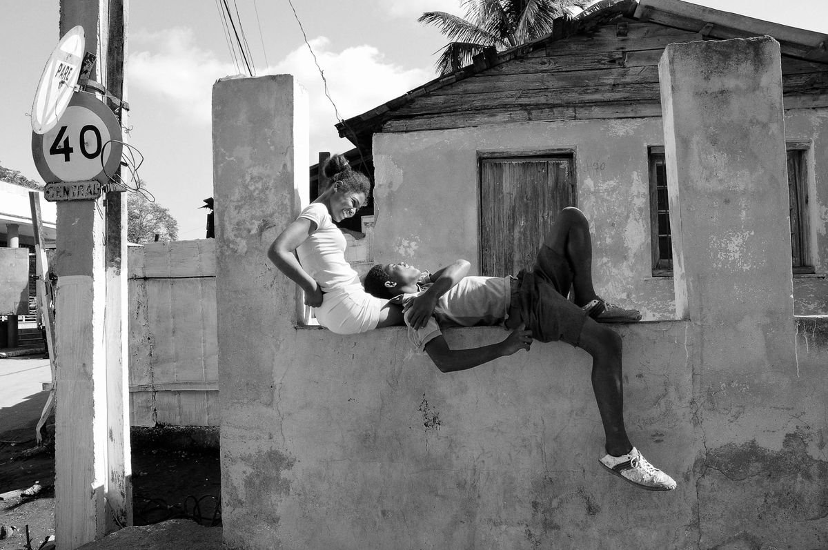 Young couple sitting on wall in the sun