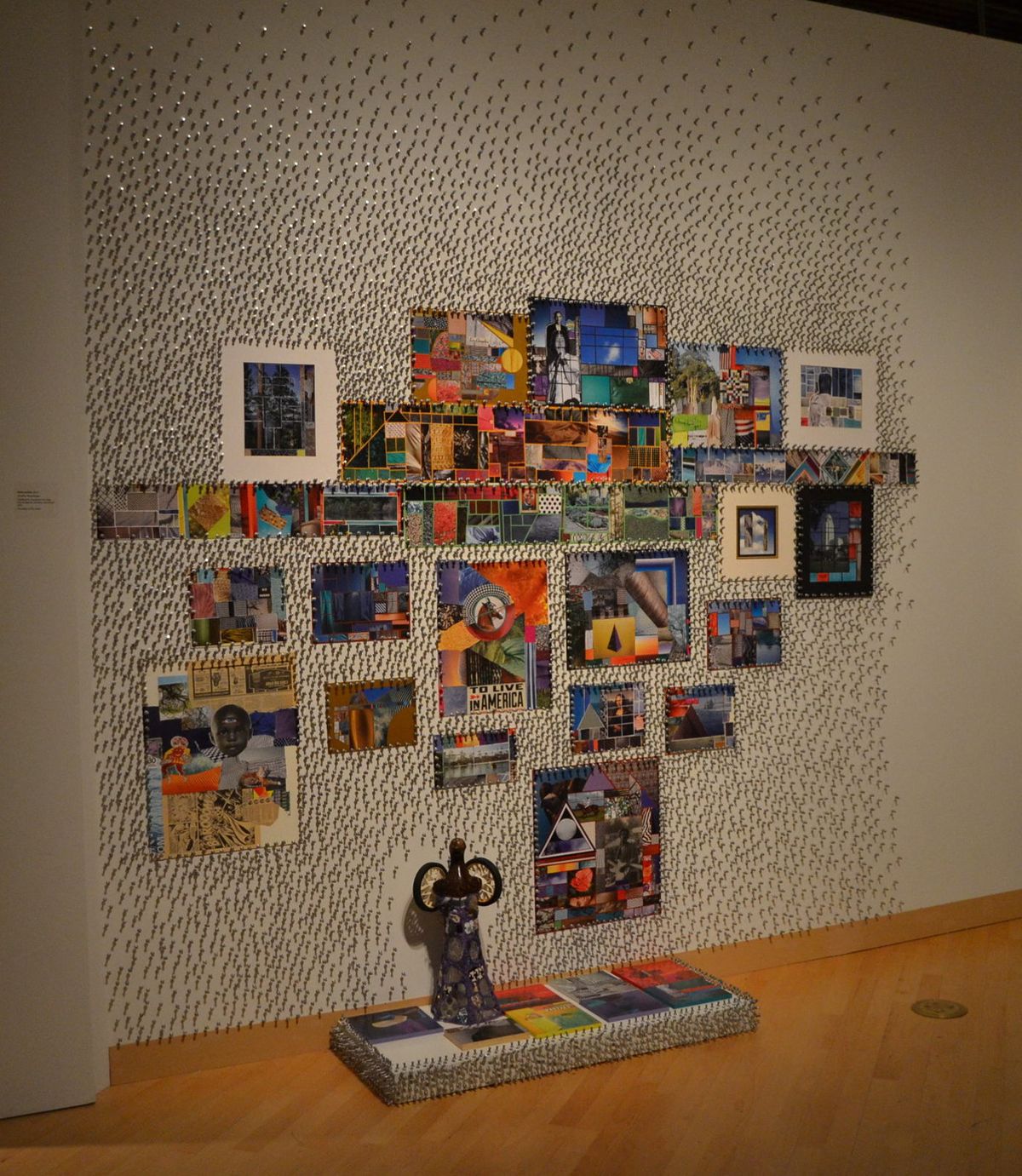 Installation of nails in wall as texture, collage of smaller framed works, and small statues