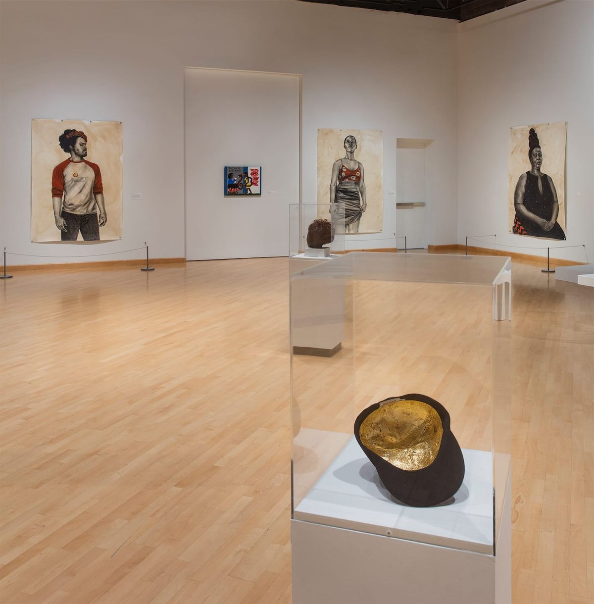 Installation view of large scale paintings, framed works, vitrines, and sculptures