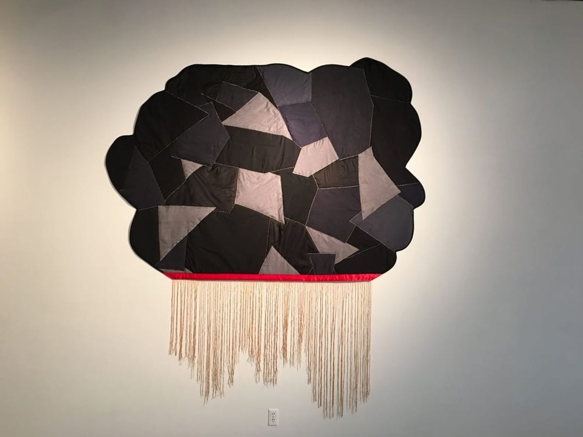 Cloud shaped patchwork in tones of black and grey with fringe as rain fall.