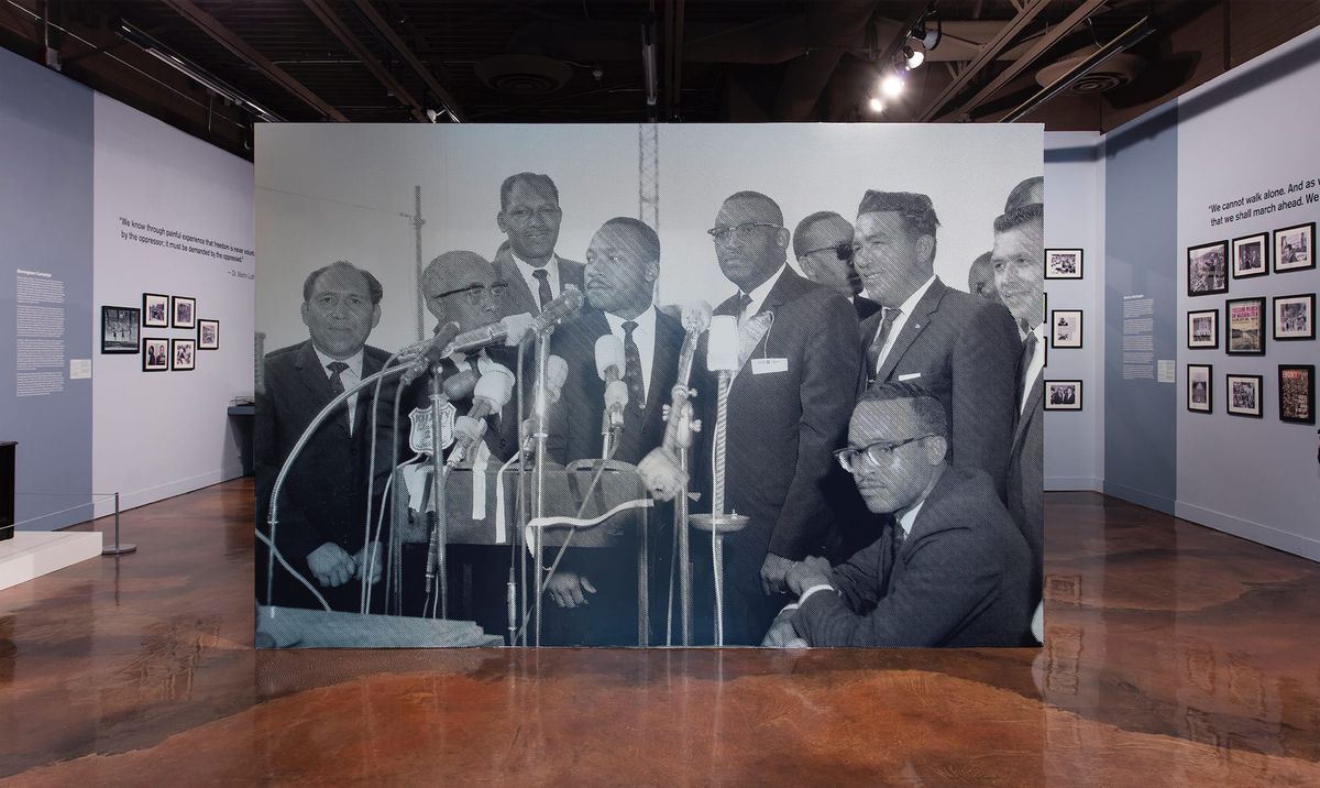 Large scale blow up of Dr. Martin Luther King Jr. at microphones with his political counterparts
