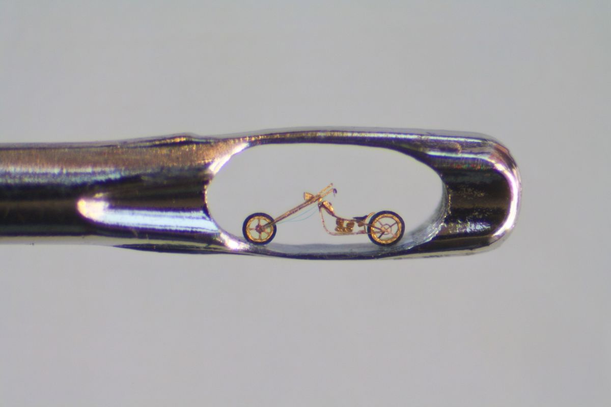 Sculpture of gold Harley chopper inside the eye of sewing needle