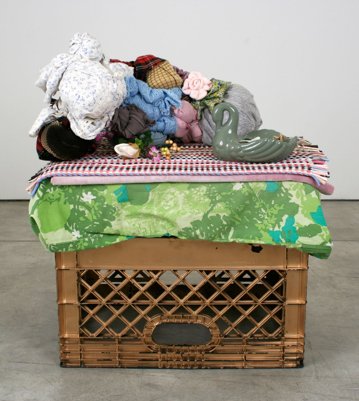 Gold milk crate serving as end table covered in pillowcase and bric-a-brac