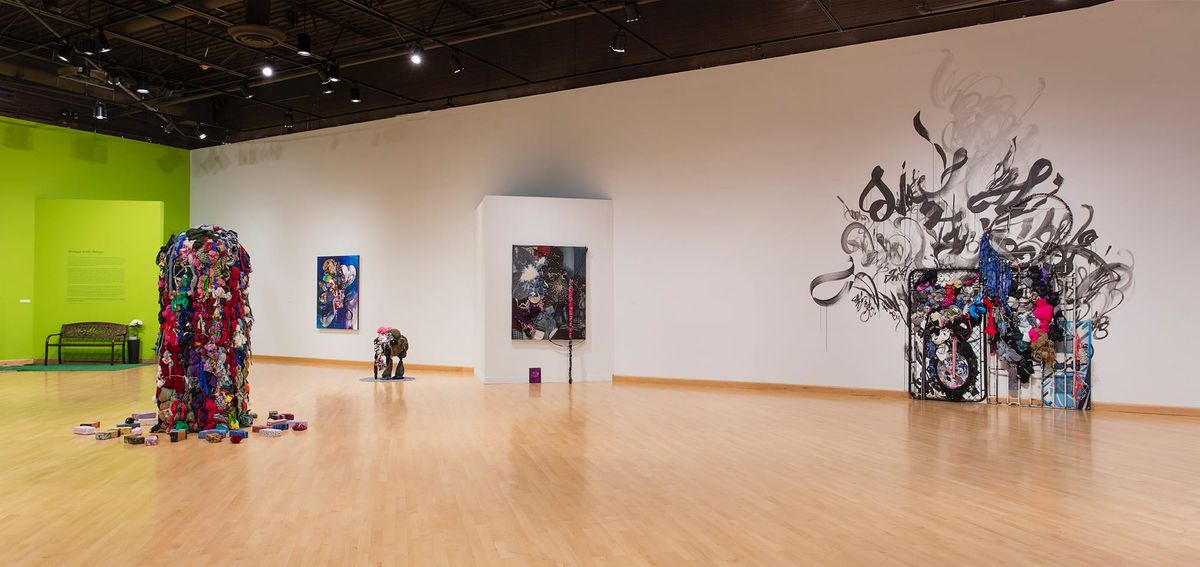 Installation view of sculptures, bench, paintings, and mixed media installation