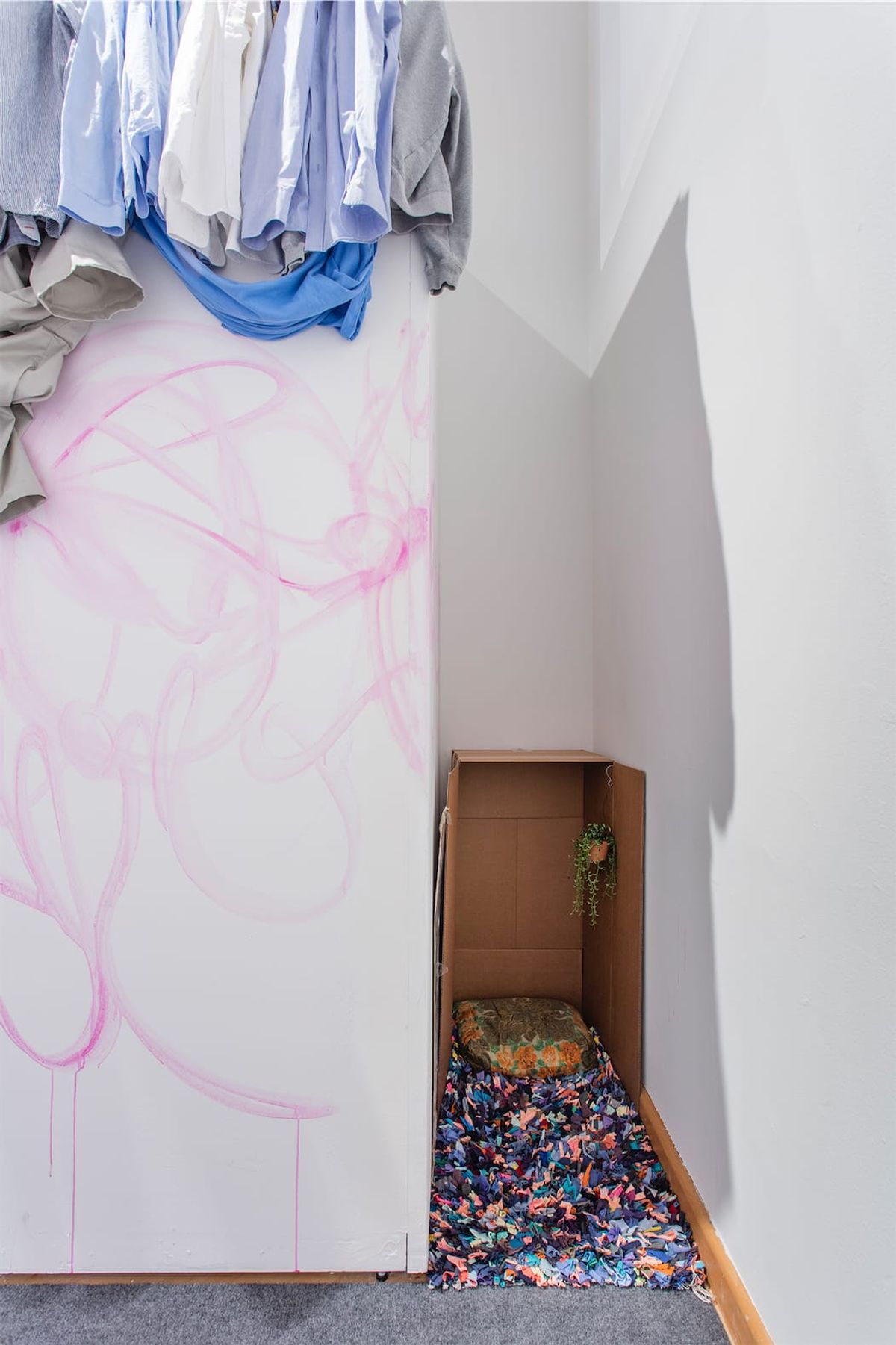 Installation view, cardboard box with cushion and rug inside