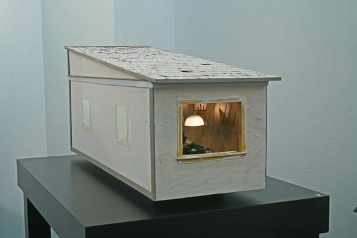 Maquette of single-windowed living structure on table
