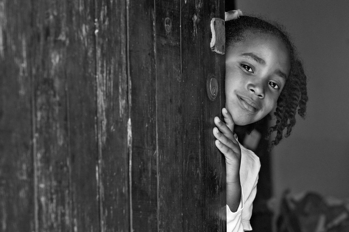 Smiling little girl peeking from behind open door