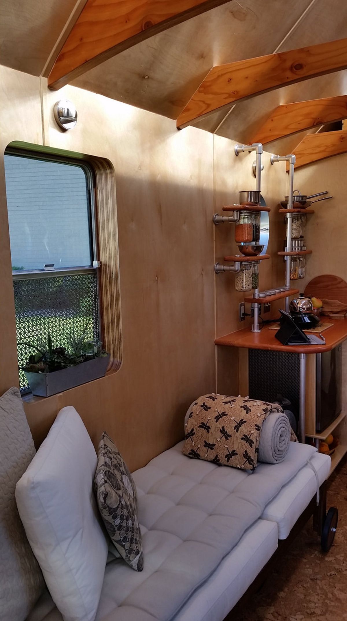 Interior view of installation showing daybed, kitchenette, and window