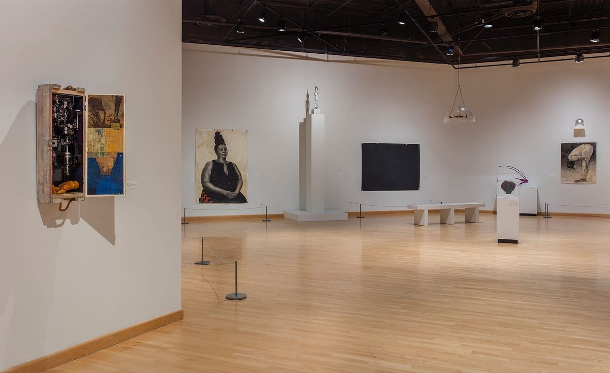 Installation view of paintings, sculpture of found objects, seating, and hanging objects