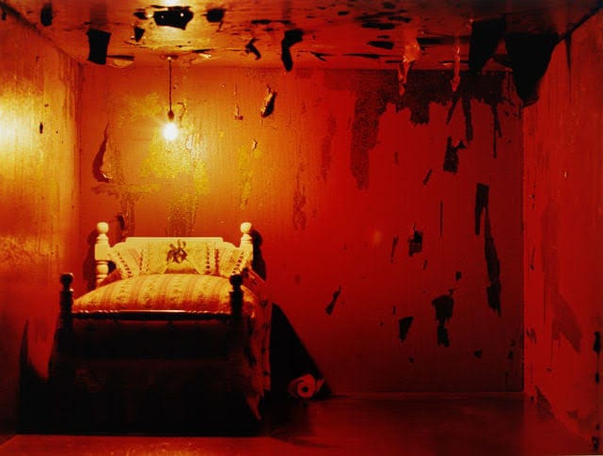 Windowless room with peeling paint and a freshly made small bed