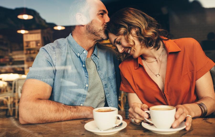 A couple shares an intimate moment over coffee in a cafe, looking happy on the surface while hiding the hidden money habits and unspoken truths tracked by personal finance statistics.