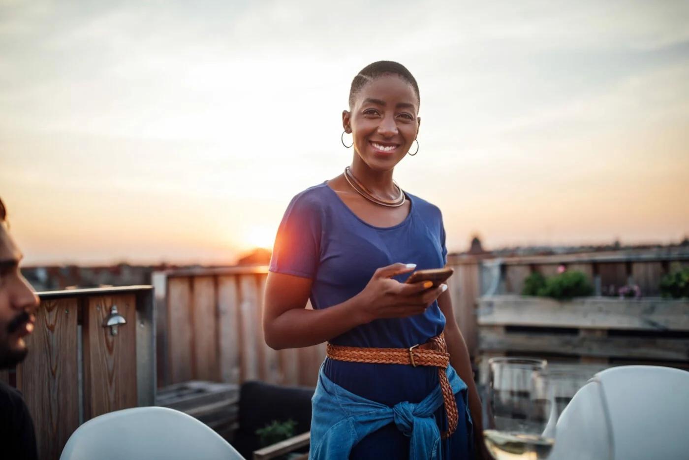 Boldin member on a rooftop at sunset holding a phone