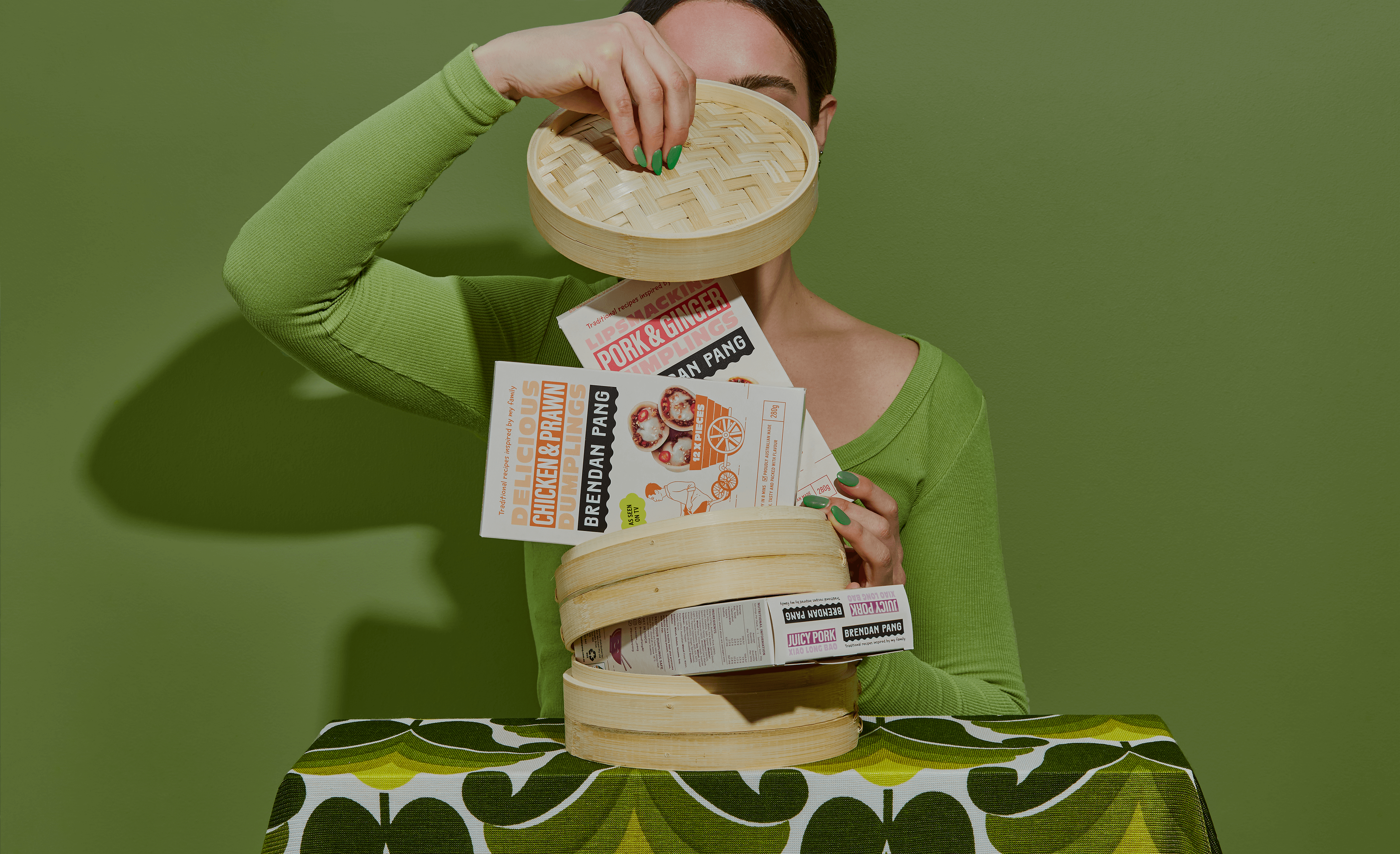 Woman opening a bamboo steaming basket revealing boxes of Brendan Pang’s dumplings. Packaging design by Sydney design studio Our Revolution.